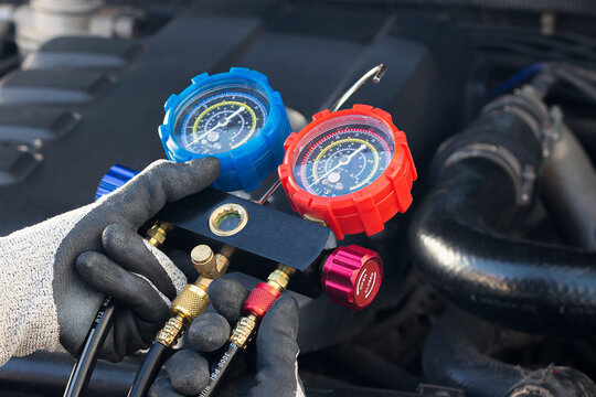 Mechanic checking car ac refrigerant with manifold gauge set