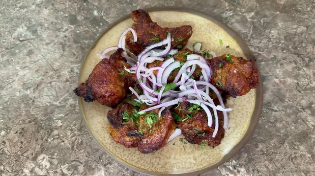 crispy grilled chicken wings on plate, topped with thinly sliced red onion and parsley, charred edges glazed with smoky marinade, rustic stone surface, closeup foodporn shot