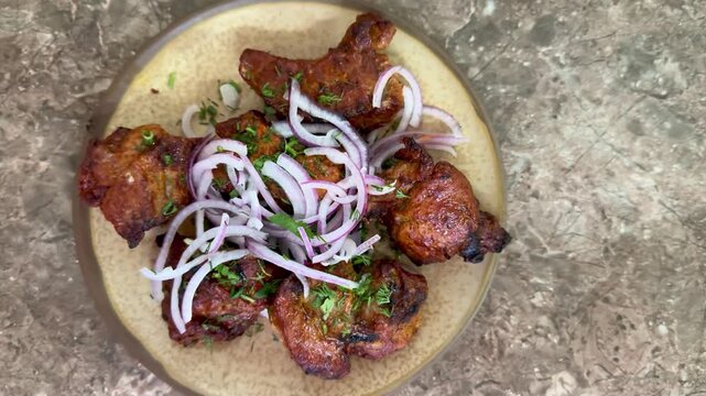 crispy grilled chicken wings on plate, topped with thinly sliced red onion and parsley, charred edges glazed with smoky marinade, rustic stone surface, closeup foodporn shot