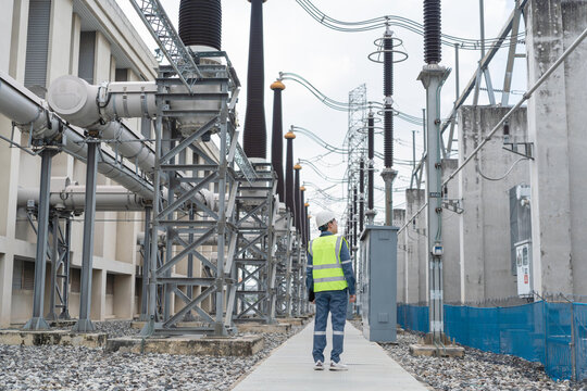 Engineer walks through high voltage substation during routine patrol, visually inspecting equipment alignment and corridor safety to maintain stable and reliable power operations.