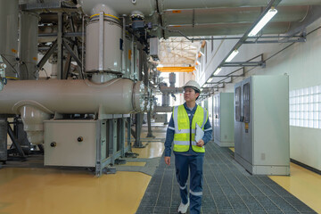 Industrial engineer walking through gas insulated switchgear facility, visually inspecting equipment condition, recording observations, and ensuring operational readiness during routine maintenance.