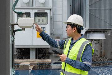 Engineer performing detailed inspection on electrical equipment at a high voltage substation, checking components, monitoring safety conditions, and recording data for power system maintenance.