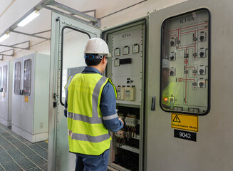 Engineer performing electrical panel inspection in a substation control room, working in maintenance mode to verify wiring, relays, and monitoring systems for safe and reliable power operation. © JD Studio