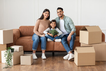 House Move And Renovation Concept. Portrait of happy loving family of three people sitting on the...