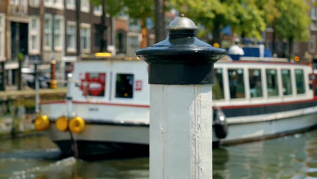 Super slow motion 4K focus shot of bollard at the IJ Amsterdam with ferry gliding the background cinematic depth of field high detail maritime 
