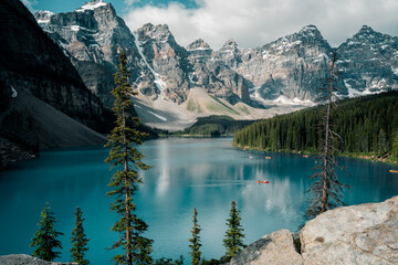 Sun-soaked Moraine Lake with colorful canoes on turquoise glacial water in Banff