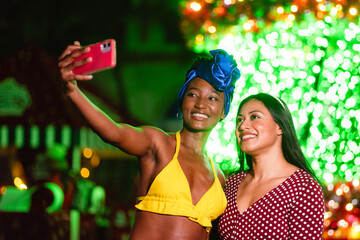 Diverse women friends taking selfie at night event