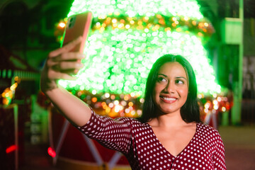 Latina woman taking selfie enjoying holiday lights