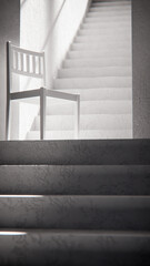 3D render of wooden chair at stair base with dramatic sunlight and shadows. Ideal for interior design, product display, and architectural visualization in minimalist style.