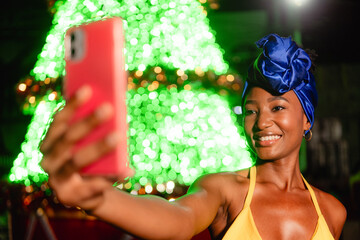 Smiling woman capturing selfie with festive holiday lights
