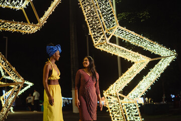 Diverse friends enjoying night out under decorative lights