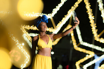 African caribbean woman taking selfie at night festive background