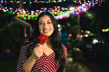Young woman smiling holding candy apple at night
