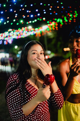 Diverse young women enjoying candy apples at night festival