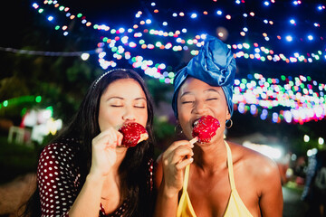Diverse friends enjoying sweet candy apples at night market