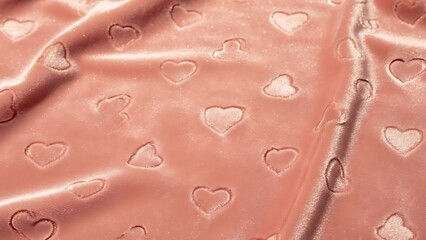 Soft pink satin fabric with embossed hearts pattern viewed from above