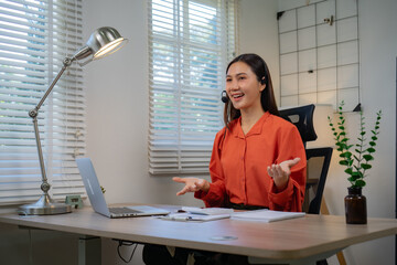 A professional-looking young woman, smiling brightly in a call center office, is wearing headphones and assisting customers with online communication, customer service, providing advice, and offering