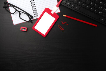 Red plastic badge with stationery on black wooden texture background. Template designed for employees of company