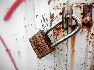 A heavily rusted padlock was used to lock a door that was also rusty