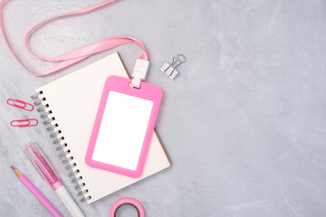 Pink plastic badge with book and stationery on white stone texture background. Template designed for employees of company