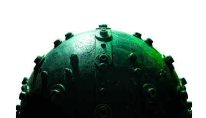 Close-up of a dark, metallic, green sphere with various protrusions