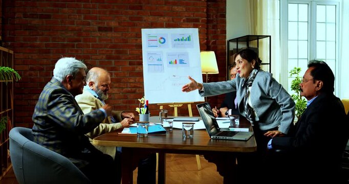 Indian business people hand shaking after deal is cracked as senior Indian Asian businessman closes successful agreement across table while smiling during corporate meeting in modern office
