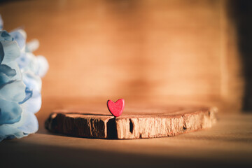 Small red heart on wooden slice with blue flowers. Romantic love concept for Valentine's Day background with copy space. Rustic vintage style decoration for wedding or holiday card design.