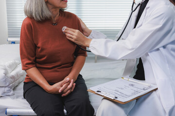 Doctor examining senior woman's chest with stethoscope