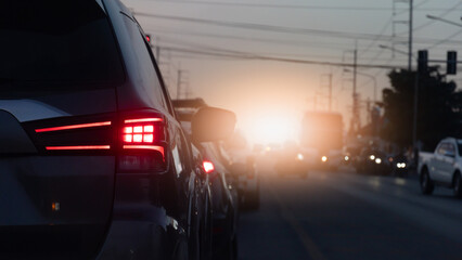 Rear side of car with red brake light on during traffic jam on the road at sunset. Rush hour transportation and driving safety concept.