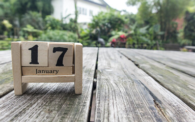 wooden cube calendar for January 17th place on old table in sunny garden background