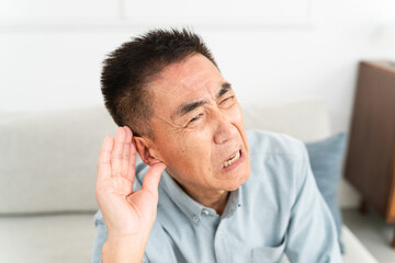 耳に手を当てて聞きかえす熟年男性