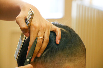 Detailed view of hairdressing tools, a metal comb, and sharp scissors in the professional hands of a stylist for kids hair cut