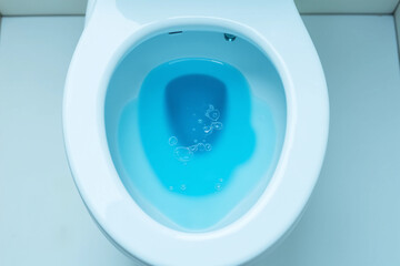 Top view of toilet bowl, blue detergent flushing in it. 3d rendering.