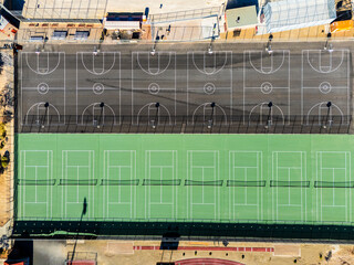Top-down aerial view of outdoor basketball and tennis courts in a desert suburban neighborhood, geometric sports facilities and urban recreation planning