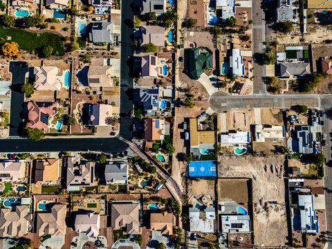 Top-down aerial view of suburban houses with private swimming pools and intersecting streets in a planned desert neighborhood
