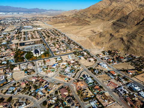Aerial view of suburban residential neighborhood in Los Angeles desert area with intersecting streets, detached houses, swimming pools, dry landscapes, and low density urban planning seen from directl