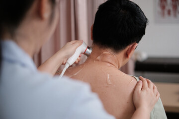 Male Asian patient is treated for healthy recovery, gel ultrasound for shoulder pain relief by female physical muscle doctor, passive medical therapy at spa clinic, and wellness massaging healthcare.