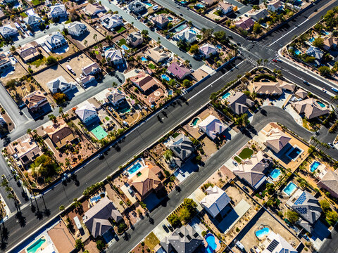 Top down aerial view of suburban homes in Los Angeles with swimming pools, solar panels, detached houses and straight residential streets in a dry desert climate environment