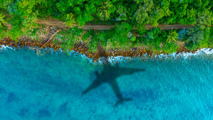 Aerial view of shadow passenger plane silhouette and sandy beach blue sea with waves at sea beach summer vacation sea travel concept	