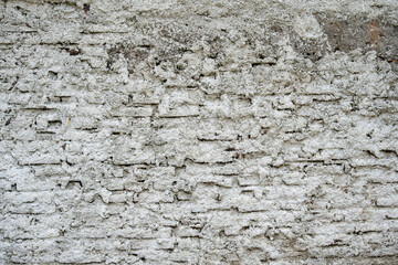 Fototapeta premium Rough texture of a white painted brick wall with weathered cement. Industrial background for architectural design and vintage urban concepts