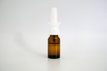 Nasal drop bottle mockup. Brown glass bottle with a white plastic cap and a spray nozzle isolated on a gray background