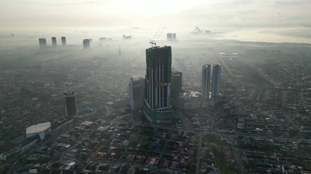 A city with a large building in the middle. The sky is cloudy and hazy. There are many buildings in the city. Aerial view Johor Bahru, Johor