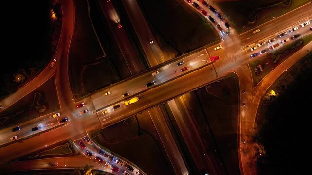 A busy highway with cars and trucks on it. The highway is lit up at night. There are many cars on the highway, including a few trucks. Aerial night view Larkin