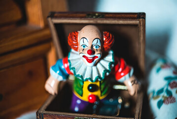 The box suddenly opens and a clown figure suddenly jumps out of it, frightening everyone around.