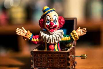 The box suddenly opens and a clown figure suddenly jumps out of it, frightening everyone around.