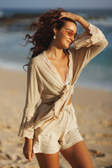 Boho Woman In Beige Summer Outfit Walking On Sandy Beach At Sunset
