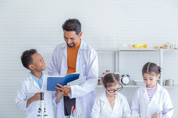 Adorable Multicultural school boy and girl students kids wearing lab coats happy study with Indian teacher sending experiment paperwork in laboratory room, lifestyle learning education science class