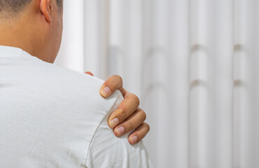Man gripping shoulder in pain—shows symptoms of shoulder strain, inflammation, or office syndrome. Ideal for ads promoting shoulder pain treatment and physical therapy.