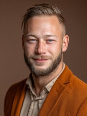 Obraz premium Premium business portrait of confident young man in orange blazer, professional headshot with natural smile on white background