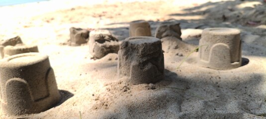 Multiple sand mounds scattered across the beach create a miniature kingdom under the shade of nearby trees
